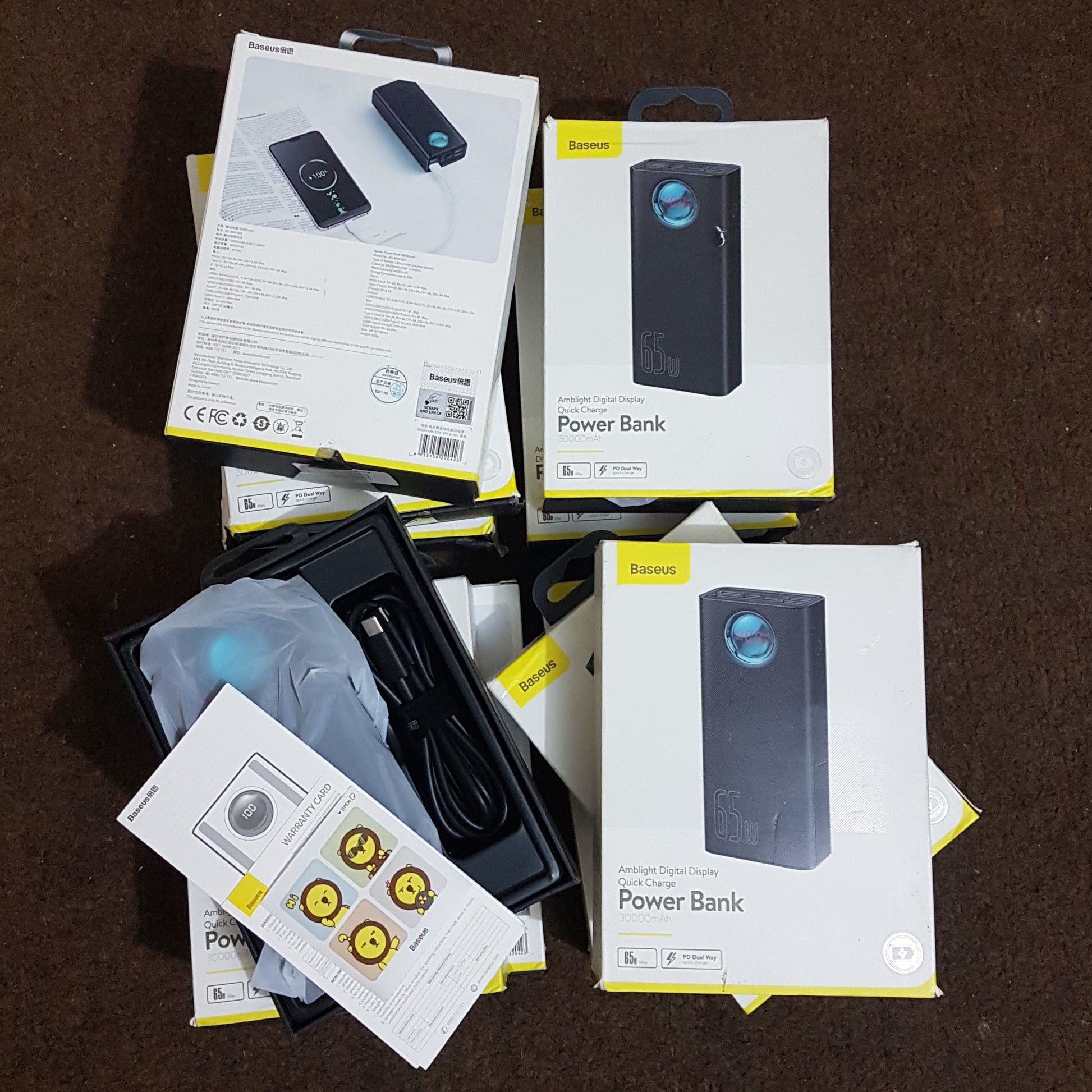 Baseus BS-30KP365 power bank boxes and contents displayed on a brown surface