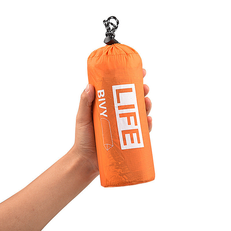 Person holding an orange Ultra Light Emergency Tent in a compact carry bag labeled "Life Bivy."