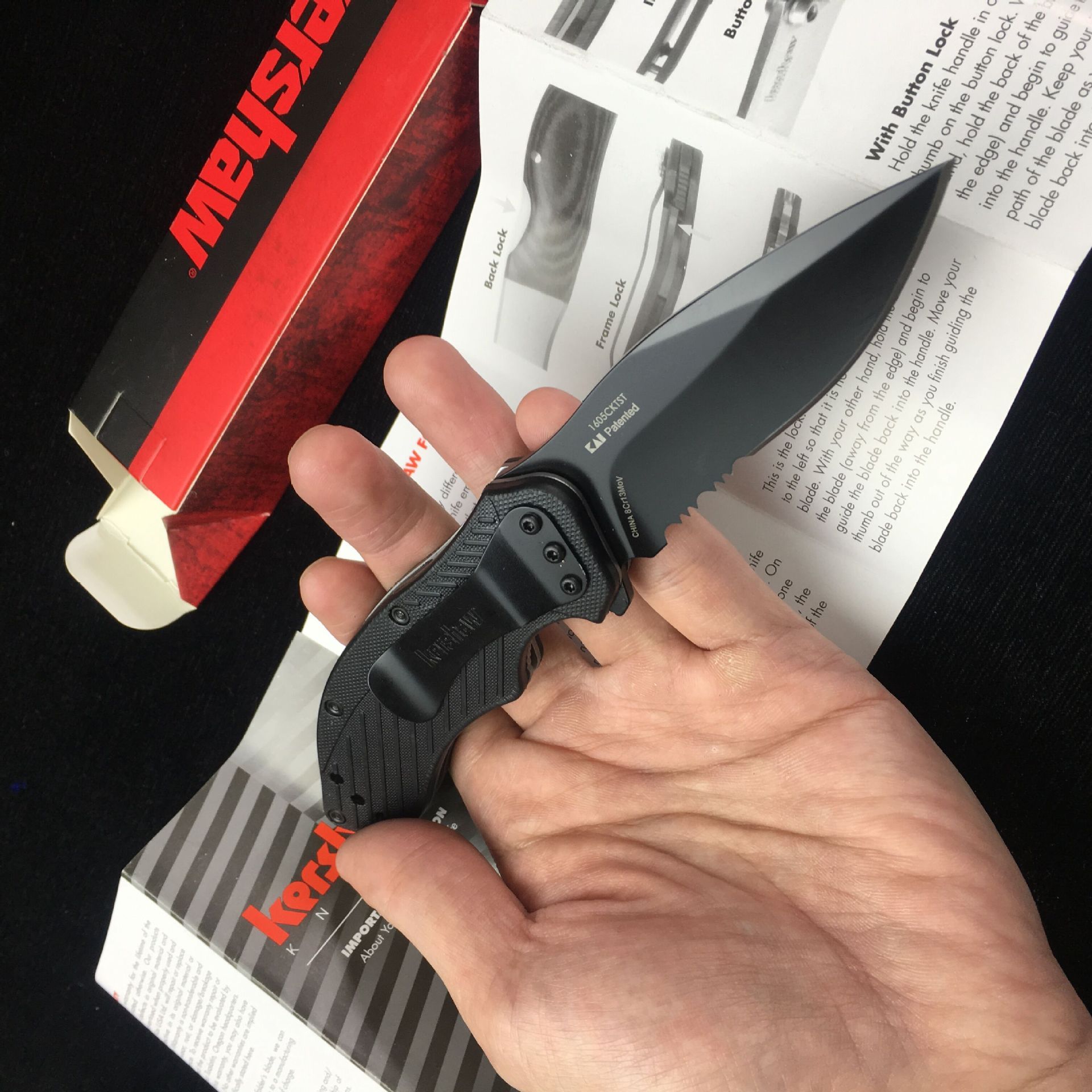 Person holding 8CR13 MOV survival folding knife with black handle and 57HRC hardness