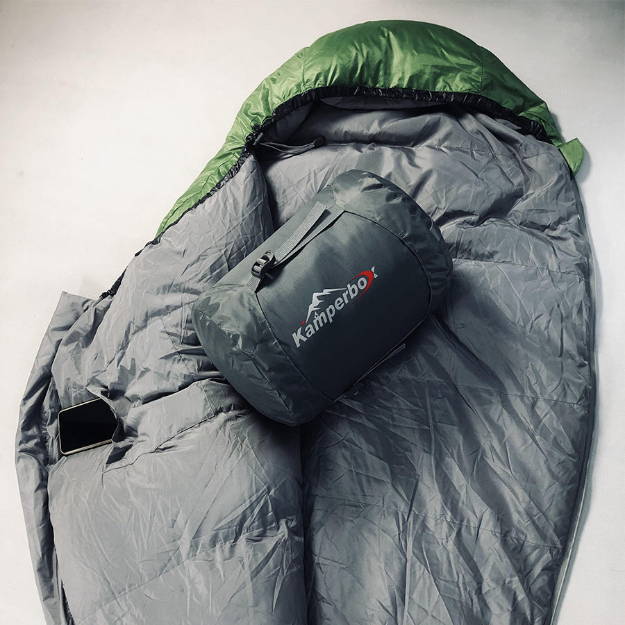 Kamperbox down sleeping bag with compression sack, showcasing its portability and warmth for camping and outdoor adventures.