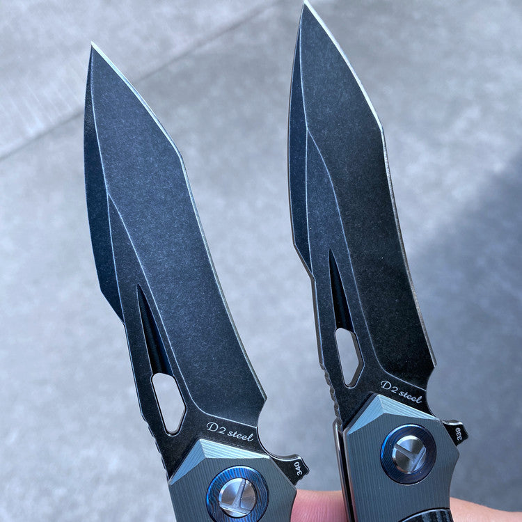 Two D2 steel survival folding knives with G10 handles, 60-61HRC hardness, and titanium damascus washers on a concrete background.