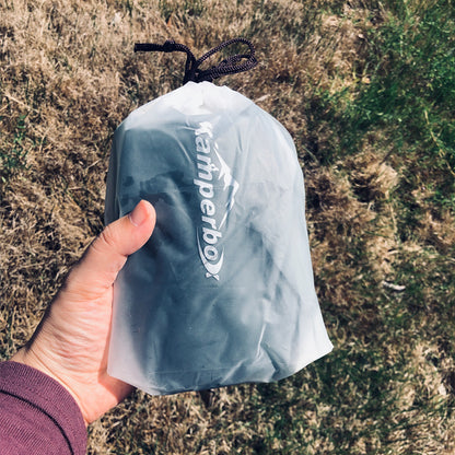 Hand holding Kamperbox Down Socks in a compact drawstring bag for camping.