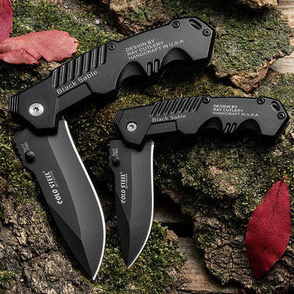 7Cr17 Mov stainless steel folding knives with black aluminum alloy handles on outdoor background