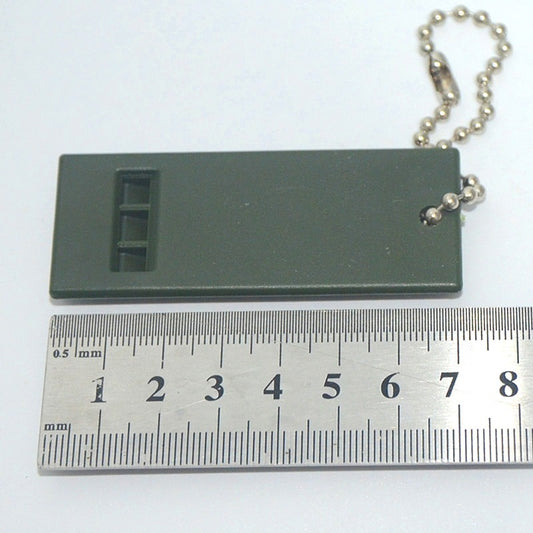 High Decibel Survival Whistle in dark green with 3-frequency design next to a ruler for size reference