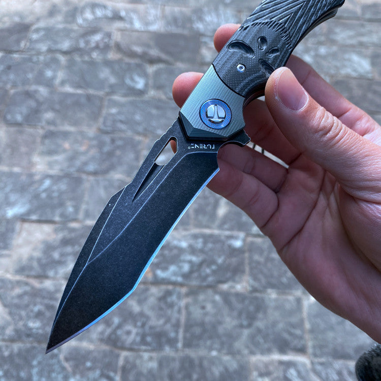 Close-up of a D2 steel survival folding knife with a G10 handle, showing the detailed blade and ergonomic design features.